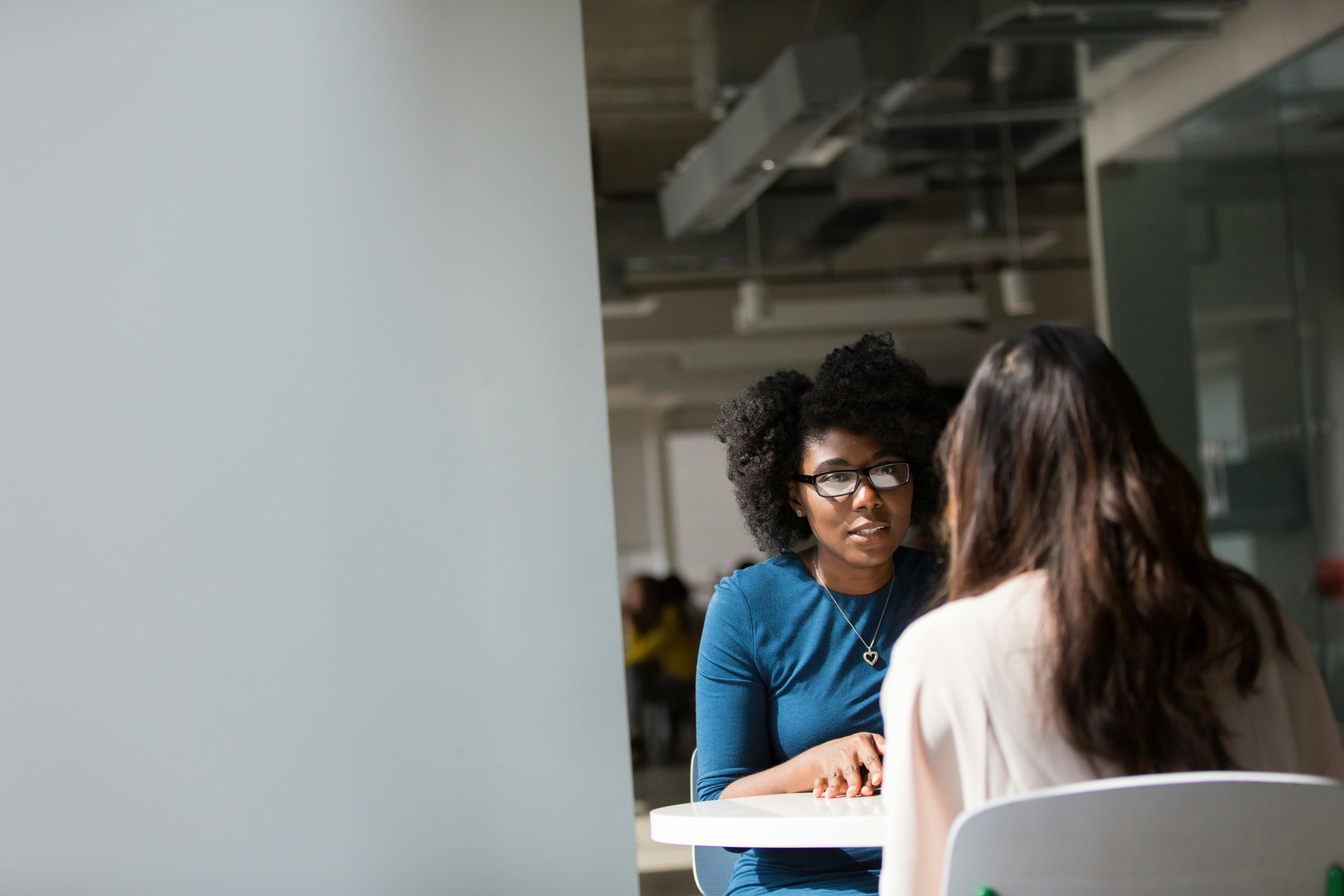 Mulheres negras conversando em uma mesa em um escritório